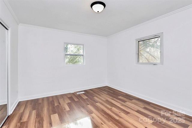 empty room featuring baseboards, wood finished floors, and crown molding