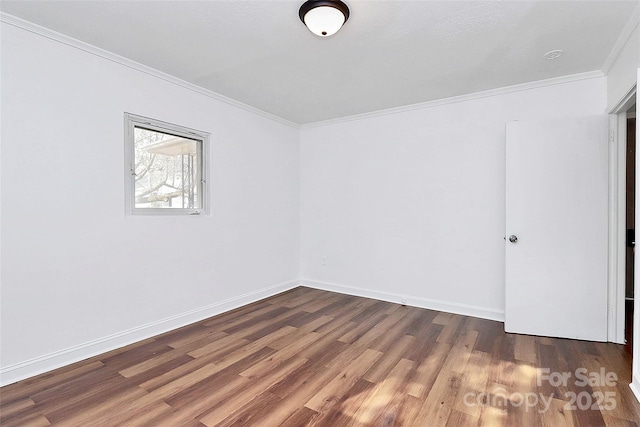 spare room featuring ornamental molding, baseboards, and wood finished floors