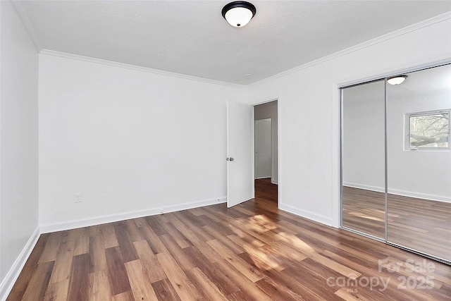 unfurnished bedroom featuring crown molding, baseboards, and wood finished floors