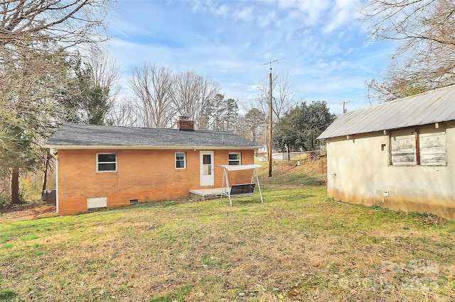 rear view of house featuring a yard, brick siding, crawl space, and a chimney