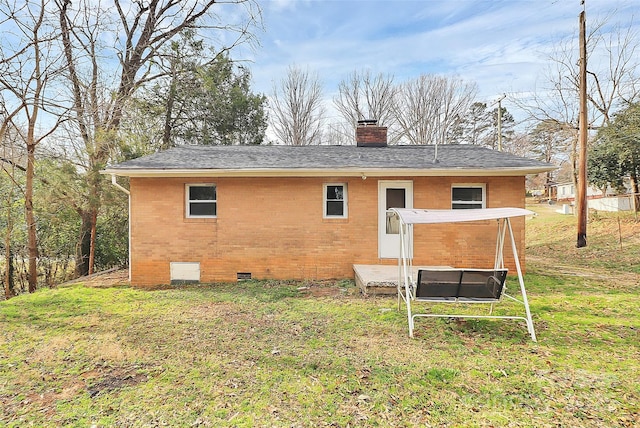 back of property with a yard, brick siding, crawl space, and a chimney