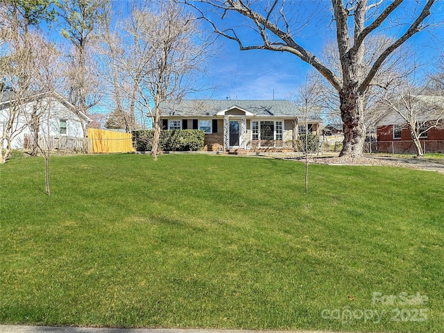 ranch-style house featuring fence and a front yard