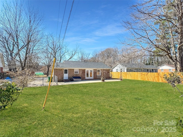 exterior space with a yard, brick siding, a patio area, and fence