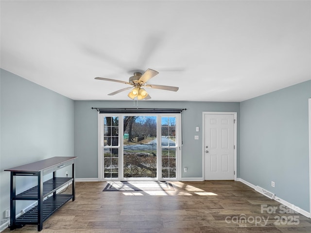 interior space with a ceiling fan, visible vents, baseboards, and wood finished floors