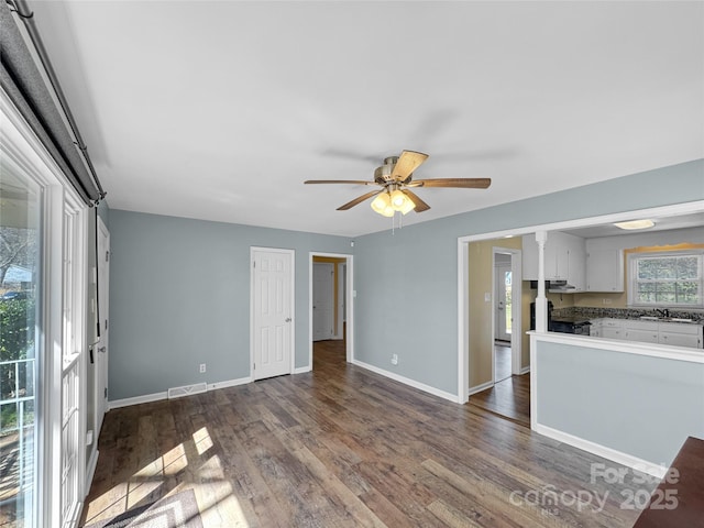 unfurnished room featuring visible vents, baseboards, a ceiling fan, dark wood-style flooring, and a sink