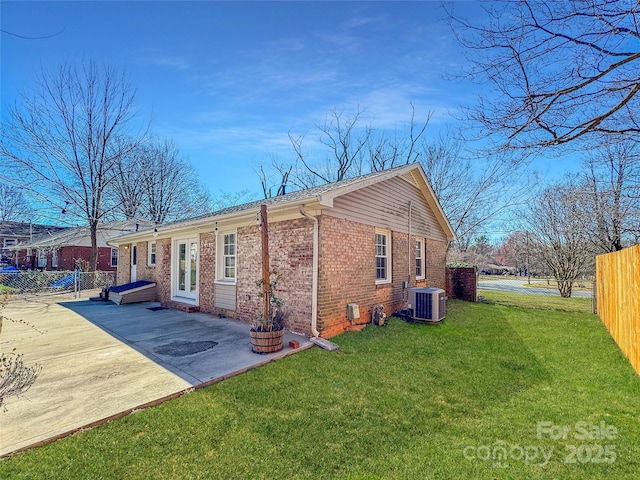 view of property exterior featuring a lawn, fence, cooling unit, a patio area, and brick siding