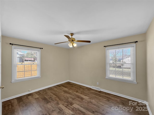 unfurnished room featuring baseboards, visible vents, ceiling fan, and dark wood-style flooring