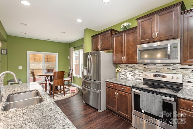 kitchen featuring dark wood finished floors, decorative backsplash, stainless steel appliances, and a sink