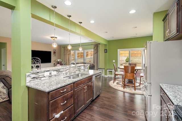 kitchen featuring stainless steel appliances, a wealth of natural light, dark wood-type flooring, and a sink