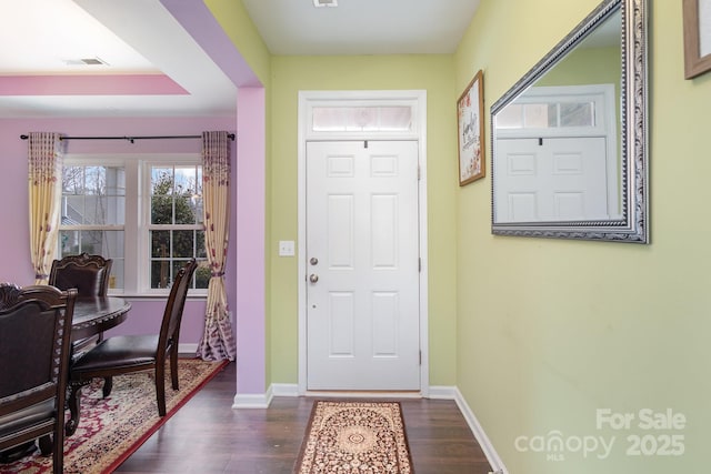 foyer entrance featuring dark wood-style flooring, visible vents, and baseboards