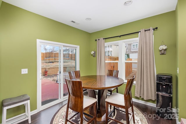 dining area with dark wood finished floors, visible vents, and baseboards