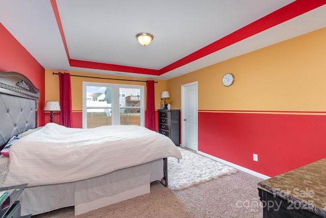 carpeted bedroom with baseboards and a tray ceiling