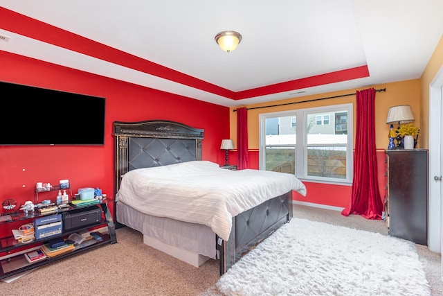 carpeted bedroom featuring visible vents and a tray ceiling