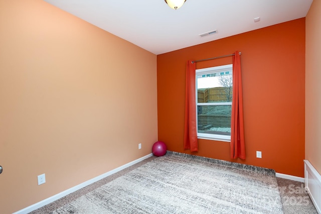 spare room with carpet, visible vents, and baseboards