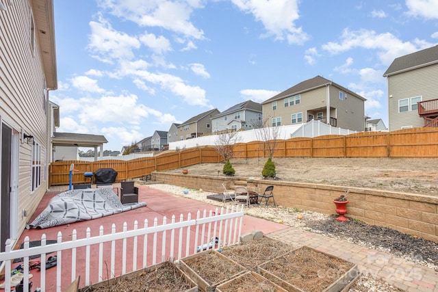 view of yard with a residential view, a garden, a fenced backyard, and a patio