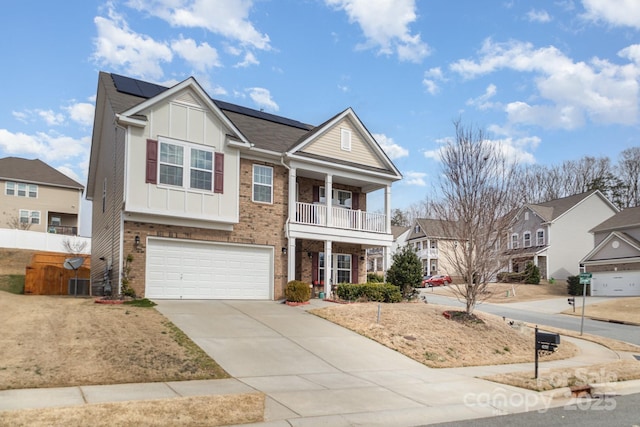 view of front facade featuring brick siding, concrete driveway, board and batten siding, roof mounted solar panels, and a balcony