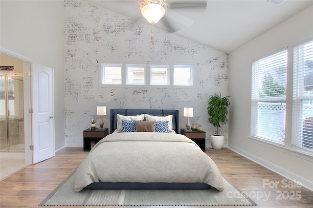 bedroom featuring wallpapered walls, vaulted ceiling, an accent wall, light wood-type flooring, and baseboards