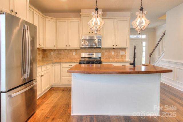 kitchen featuring a sink, wood counters, an inviting chandelier, stainless steel appliances, and light wood-style flooring