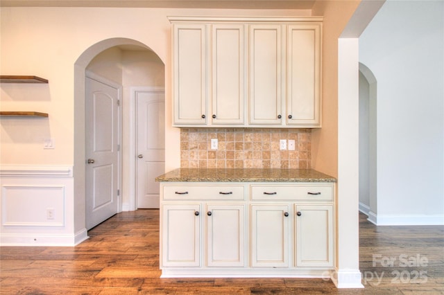 kitchen with tasteful backsplash, baseboards, wood finished floors, light stone counters, and open shelves