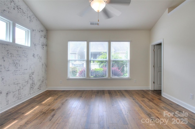unfurnished room with wood finished floors, visible vents, a wealth of natural light, and ceiling fan