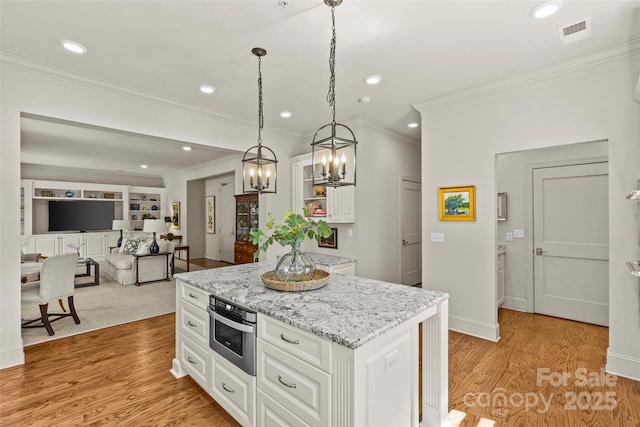 kitchen with light wood-type flooring, visible vents, hanging light fixtures, and white cabinetry