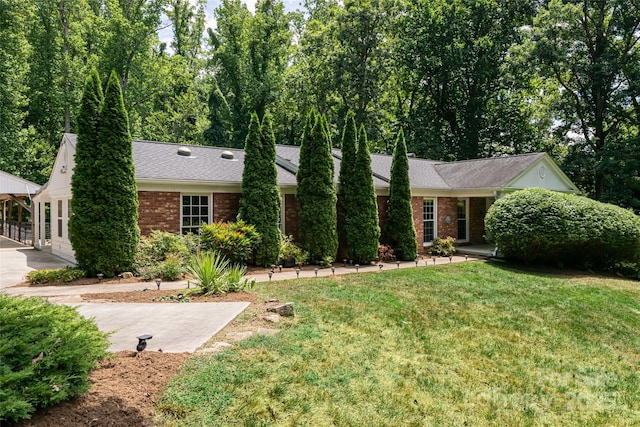 single story home with a front yard, brick siding, and roof with shingles