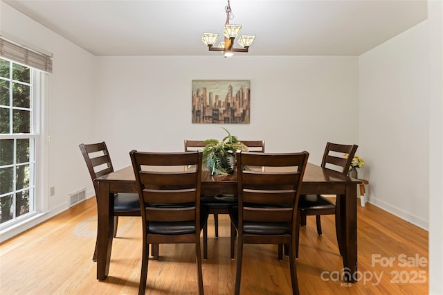 dining space with a chandelier, light wood finished floors, visible vents, and baseboards