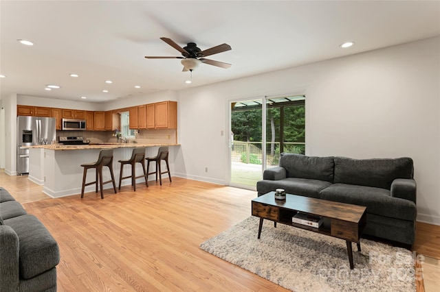 living area featuring a ceiling fan, light wood-type flooring, baseboards, and recessed lighting