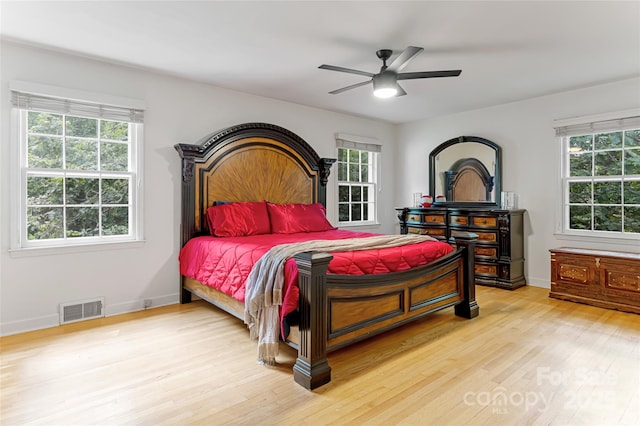 bedroom with a ceiling fan, light wood-type flooring, visible vents, and baseboards