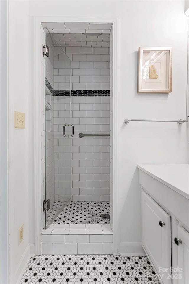 full bath featuring a stall shower, tile patterned flooring, vanity, and baseboards