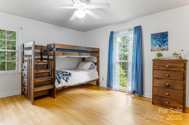 bedroom with light wood-style flooring, baseboards, and a ceiling fan