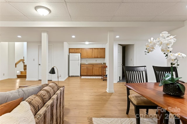 living area with light wood-style floors, stairs, a drop ceiling, and recessed lighting