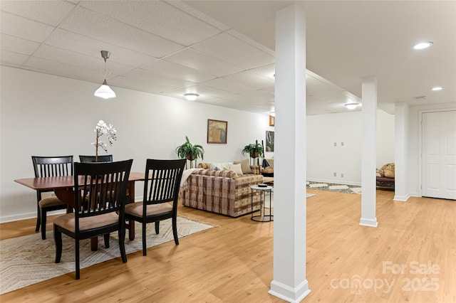 dining room featuring light wood-type flooring, baseboards, and a paneled ceiling