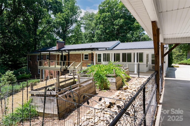 ranch-style home with brick siding, a chimney, fence, and a garden