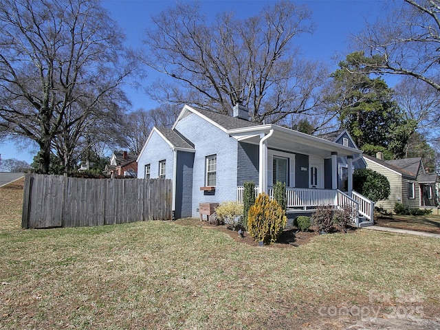 view of property exterior featuring a yard, brick siding, a porch, and fence