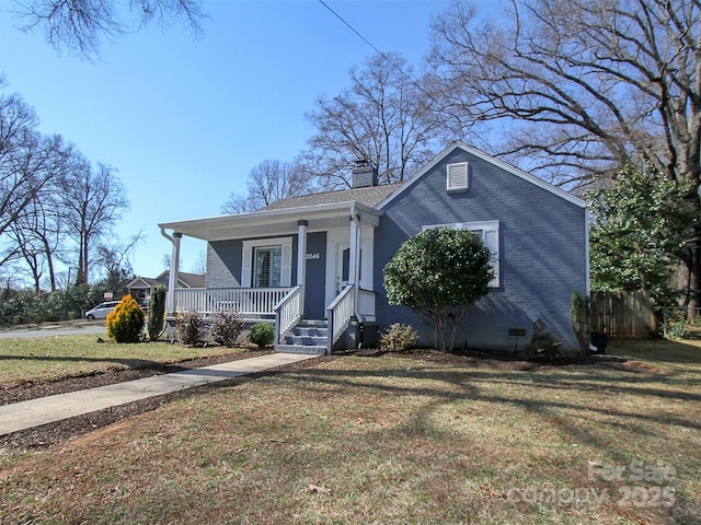 bungalow-style home featuring a chimney, a porch, crawl space, a front lawn, and brick siding