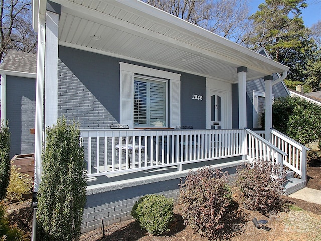 entrance to property featuring brick siding and a porch