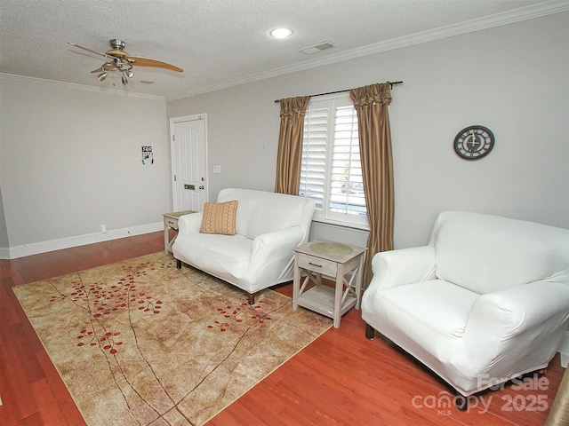 living room featuring baseboards, visible vents, wood finished floors, crown molding, and a textured ceiling