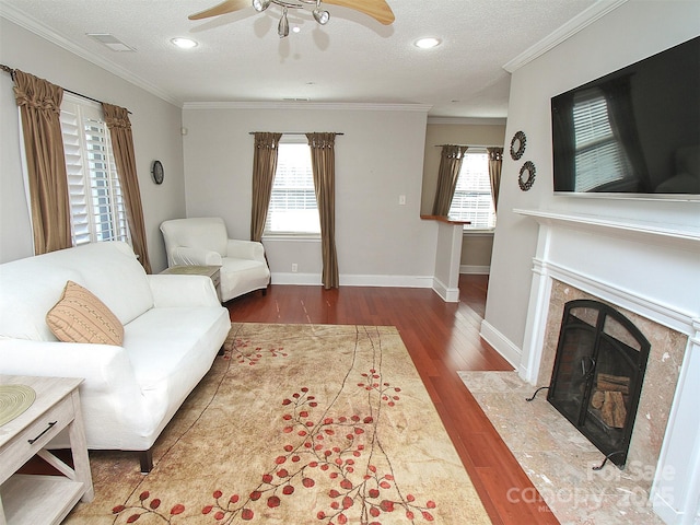 living room with ornamental molding, a wealth of natural light, wood finished floors, and a premium fireplace