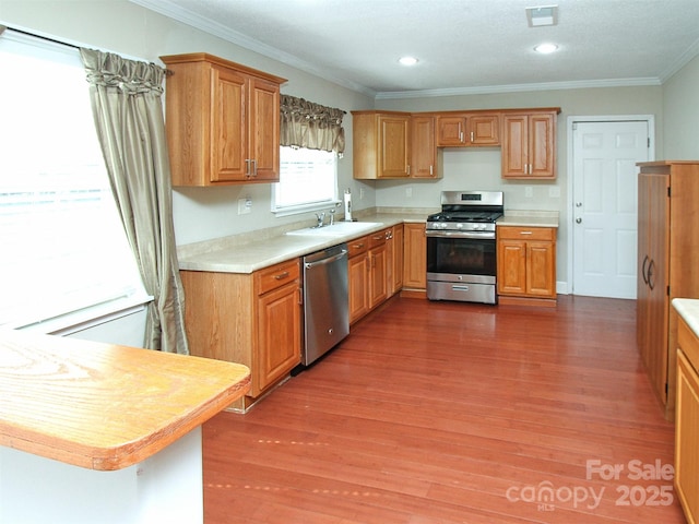 kitchen featuring light countertops, appliances with stainless steel finishes, wood finished floors, and crown molding