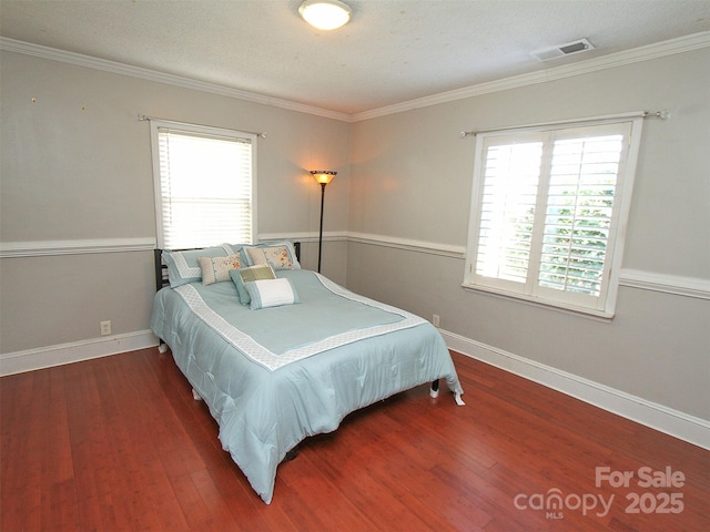 bedroom with baseboards, multiple windows, visible vents, and wood finished floors