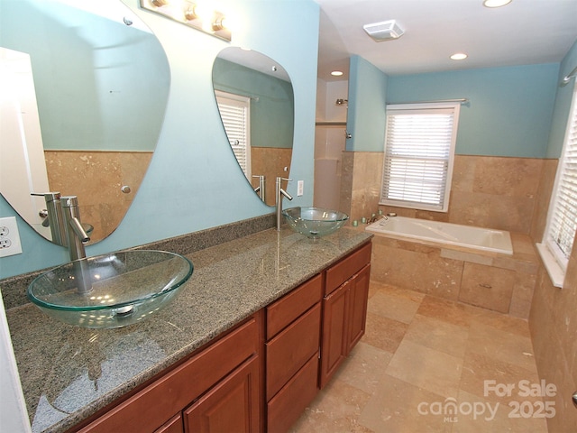 full bathroom with a bath, double vanity, visible vents, and a sink