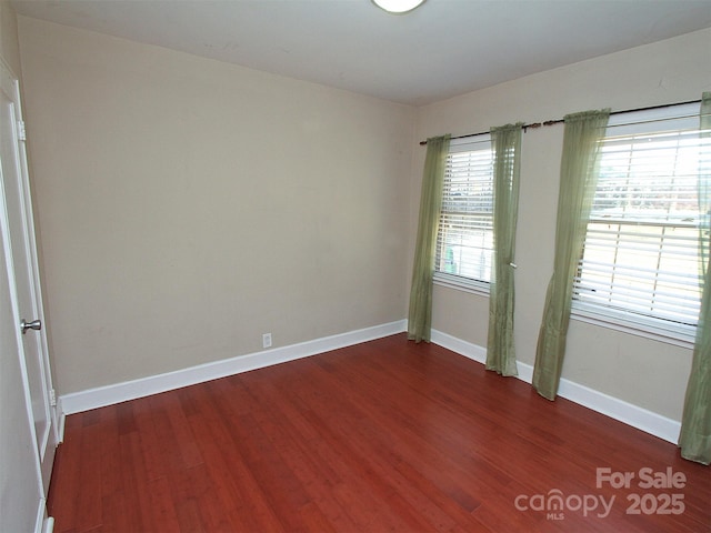 spare room featuring dark wood finished floors and baseboards