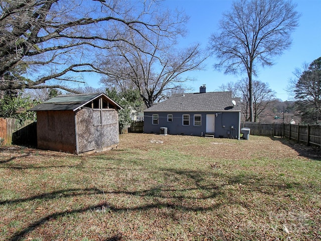 view of yard with a fenced backyard, an outdoor structure, central AC unit, and a shed