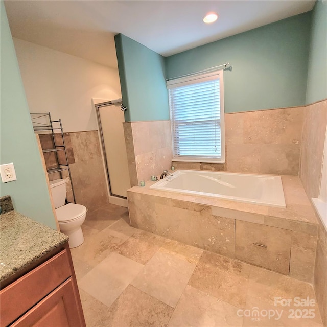 full bath featuring toilet, a bath, vanity, a shower stall, and tile walls