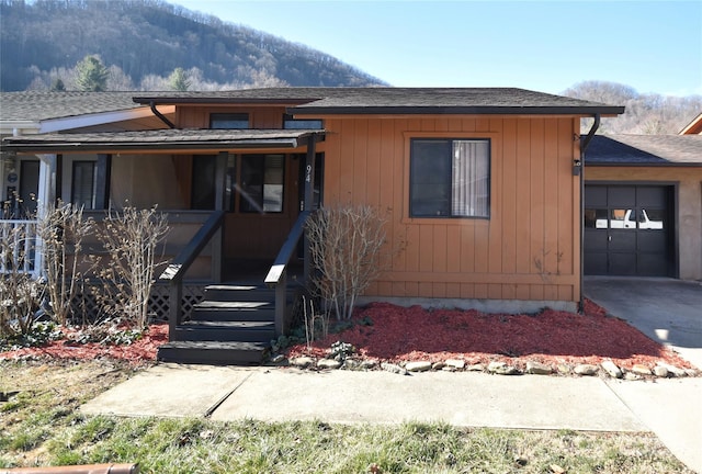 view of front of home featuring a garage, concrete driveway, roof with shingles, and a mountain view