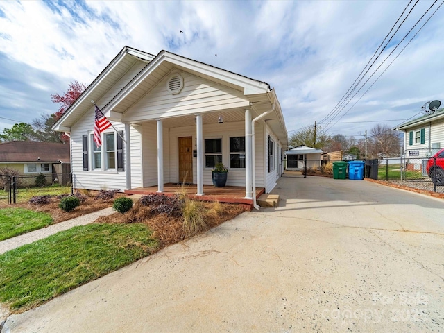 bungalow-style house with fence, covered porch, and driveway