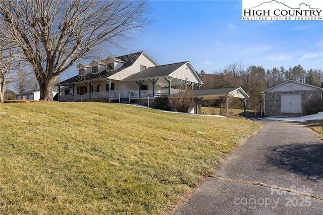 view of front of home with a shed, an outdoor structure, aphalt driveway, and a front yard