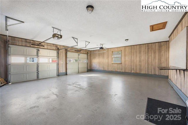 garage featuring a garage door opener, wooden walls, and baseboards