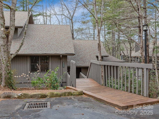 view of front facade featuring a wooden deck and a shingled roof